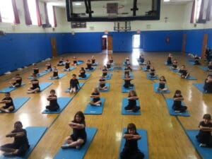 Children practicing yoga in a gymnasium.